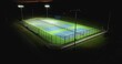 Evening aerial video of outdoor blue tennis courts with pickleball lines with lights turned on.	