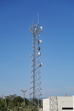 Telecommunication Tower With Many Antennas Against Blue Sky.