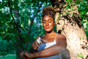 Wall Mural - Woman applying insect repellent against mosquito and tick on her arms during hike in nature. Skin protection against insect bite