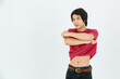 Studio shot of Asian young handsome confident slim teenager male model in casual street style outfit standing holding hands taking stripping t shirt off showing muscular abdomen on white background