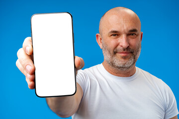 middle-aged man showing blank smartphone screen with copy space against blue background