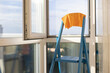 Orange rag on a blue ladder near panoramic window in apartment.