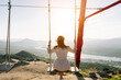 Young woman on a swing looking a beautiful landscape