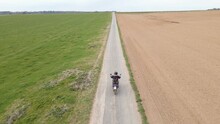 Drone Actively Tracking An Accelerating Motorcycle Rider Along An Empty Gravel Road In The European Countryside.
