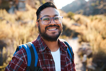 An Attractive Adult Man Smiles To The Camera While Hiking Backpacking In Nature