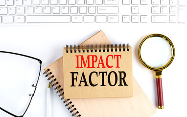 Poster - IMPACT FACTOR text in the office notebook with keyboard, magnifier and glasses , business concept