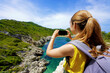 © zigres - Young hiker girl taking photo with smartphone of natural tropical landscape. Wide angle.