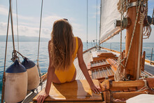 Woman in yellow swimwear looking at the ocean view sitting on a boat. Woman in yellow swimwear sitting on boat looking at the view. Woman enjoying the ocean view from a boat on a cruise