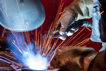 Workers wearing industrial uniforms and Welded Iron Mask at Steel welding plants, industrial safety first concept.