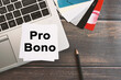 Pro Bono inscription on a sheet of notepad. Laptop computer and credit card