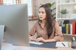 © Pormezz - Young adult asian woman working on computer at home.