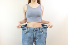 Person Wearing Oversized Old Jean Pants Before Weight Loss Success Isolated On Background.
