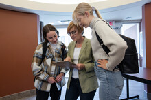 Woman With Clipboard Talking With College Students
