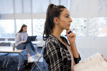 Thoughtful Young Female College Student Studying At Whiteboard