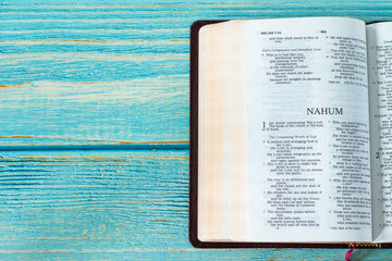 Nahum open Holy Bible Book on a rustic wooden background with copy space. Top table view. Old Testament Scripture prophecy study, Christian biblical concept.	