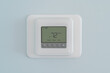 Photograph of a modern residential programmable heating and cooling thermostat set at 72 degrees mounted on a blue wall