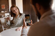 © Andrii Lysenko - couple in love sitting in cafe, male photographer photographing woman on smartphone with a cup of coffee , indoor mobile photography, Social media blog introduction concept