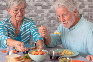 Beautiful senior couple sitting at table having brunch together at home