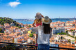 Leinwandbild Motiv A tourist mother and her little daughter enjoy the view of the beautiful cityscape of Lisbon, with the colorful houses and roofs, Portugal