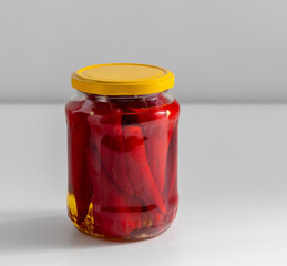 Wall Mural - food, storage and preserve concept - close up of jar with pickled red hot chili peppers on table