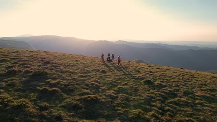 Wall Mural - Flying over group of happy hikers enjoying the sunny morning from the mountain top