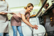 Happy mother and daughter placing dishes in dishwasher at kitchen.