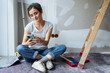 Young woman looks at her phone for ideas on how to renovate her apartment