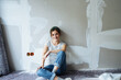 © contrastwerkstatt - Young woman sitting in the floor, renovating her apartment and looking at the camera