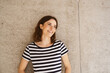 © contrastwerkstatt - Young woman stands in front of modern brown wall and looks to the side laughing