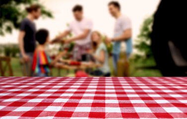 Wall Mural - Table with checkered picnic cloth outdoors on sunny day. Space for design