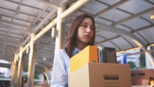 Portrait Of Young Asian Woman Walking And Holding Box Of Items After Being Laid Off From Job Due To Recession And Economic Stress In Industry