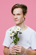 © Tatiana - close-up portrait of a happy guy with large, white daisies in his hands on a pink background with space for text