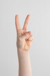 © Alexander - child hand counting and showing two finger up against white and gray background. peace gesture or victory, V sign