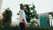 © Andrii Nekrasov - Mature businessman with neat beard wearing white shirt stands in the financial district in the city. Successful man looks around on modern buildings background