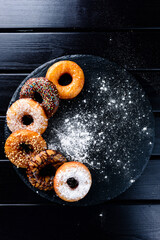 Wall Mural - Set of assorted colorful donuts on a black table with a copy space