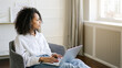 © D'Action Images - Portrait beautiful young african american girl sitting in the living room and working on laptop. Remote Work, Home Office Concept