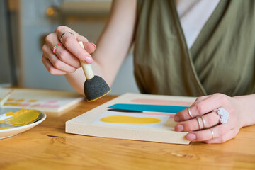 Aufkleber - Hands of young creative woman holding sponge for applying gouache over paper while working over new abstract painting by table
