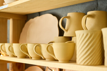 Aufkleber - Part of display consisting of several wooden shelves with handmade earthenware such as cups, mugs and plates in souvenir shop