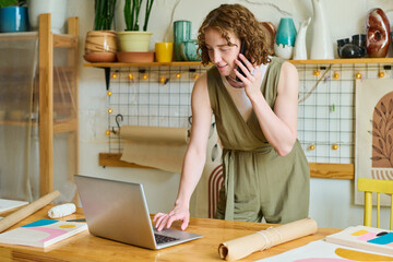 Aufkleber - Young smiling female owner of handcraft shop bending over table with laptop and checking information about order of client