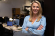 © Wavebreak Media - Portrait of smiling confident female professional with arms crossed standing in office at night