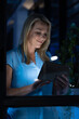 © Wavebreak Media - Smiling caucasian businesswoman working digital tablet in office at night seen through window glass