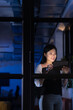 © Wavebreak Media - Asian businesswoman working over digital tablet by window in office at night seen through glass