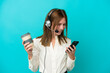 © luismolinero - Telemarketer English woman working with a headset isolated on blue background holding coffee to take away and a mobile