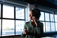 Smiling African American Young Businesswoman Talking On Mobile Phone In Creative Office