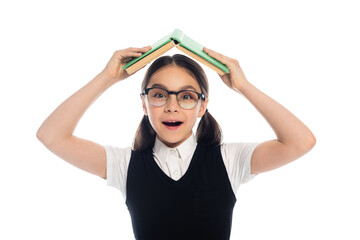 Canvas Print - Positive schoolkid in eyeglasses holding book above head isolated on white.