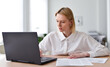 © undrey - Young woman working on laptop in living room.