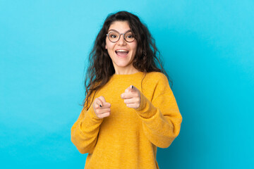 Wall Mural - Teenager Russian girl isolated on blue background surprised and pointing front