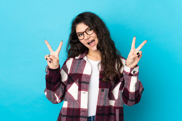 Wall Mural - Teenager Russian girl isolated on blue background showing victory sign with both hands