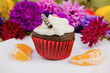 Chocolate cupcake with white cream on plate, colorful flowers in the background