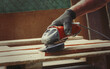 Close-up shot of a man sanding a wood board with an angle grinder at workshop, woodworking scene